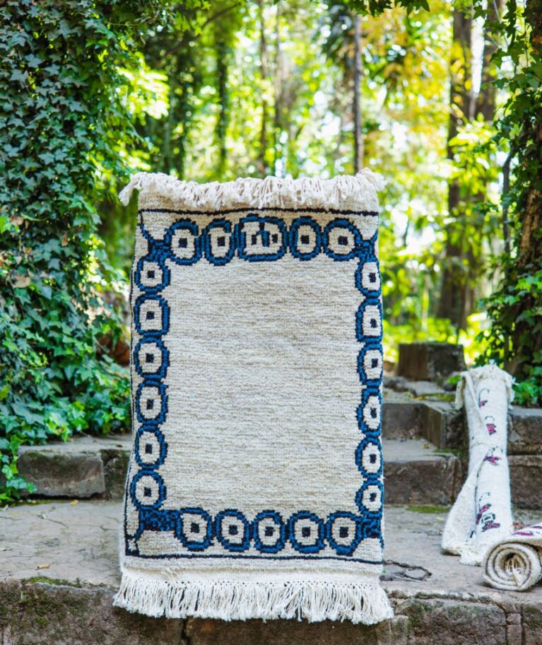 Deep blue circular motifs resembling the centers of the eye or the heart of flowers act as a protective portal, creating a sacred interior space. This instinctual design signals a safe spot built through repetitive, careful work.